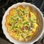 Homemade breakfast quiche with eggs, cheese, and vegetables in a golden flaky crust.
